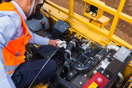 Mecânico realizando manutenção no motor de um harvester de esteira